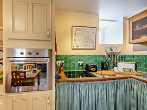 A kitchen with a built-in oven, a map on the wall, and a breakfast setup on the counter. - 2 Bed in Kirkby Stephen (oc-sz478) (Newbiggin-on-Lune)