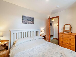 A bedroom with a bed, a dresser, a nightstand, a lamp, a mirror, and a painting on the wall. - 2 Bed in Kirkby Stephen (oc-sz478) (Newbiggin-on-Lune)