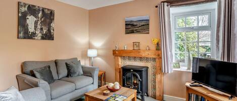 A living room with a sofa, a fireplace, a television, and a bookshelf.