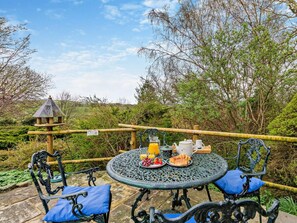 An outdoor dining area with a round metal table, blue cushioned chairs, and a variety of food and drink items. - 2 Bed in Kirkby Stephen (oc-sz478) (Newbiggin-on-Lune)
