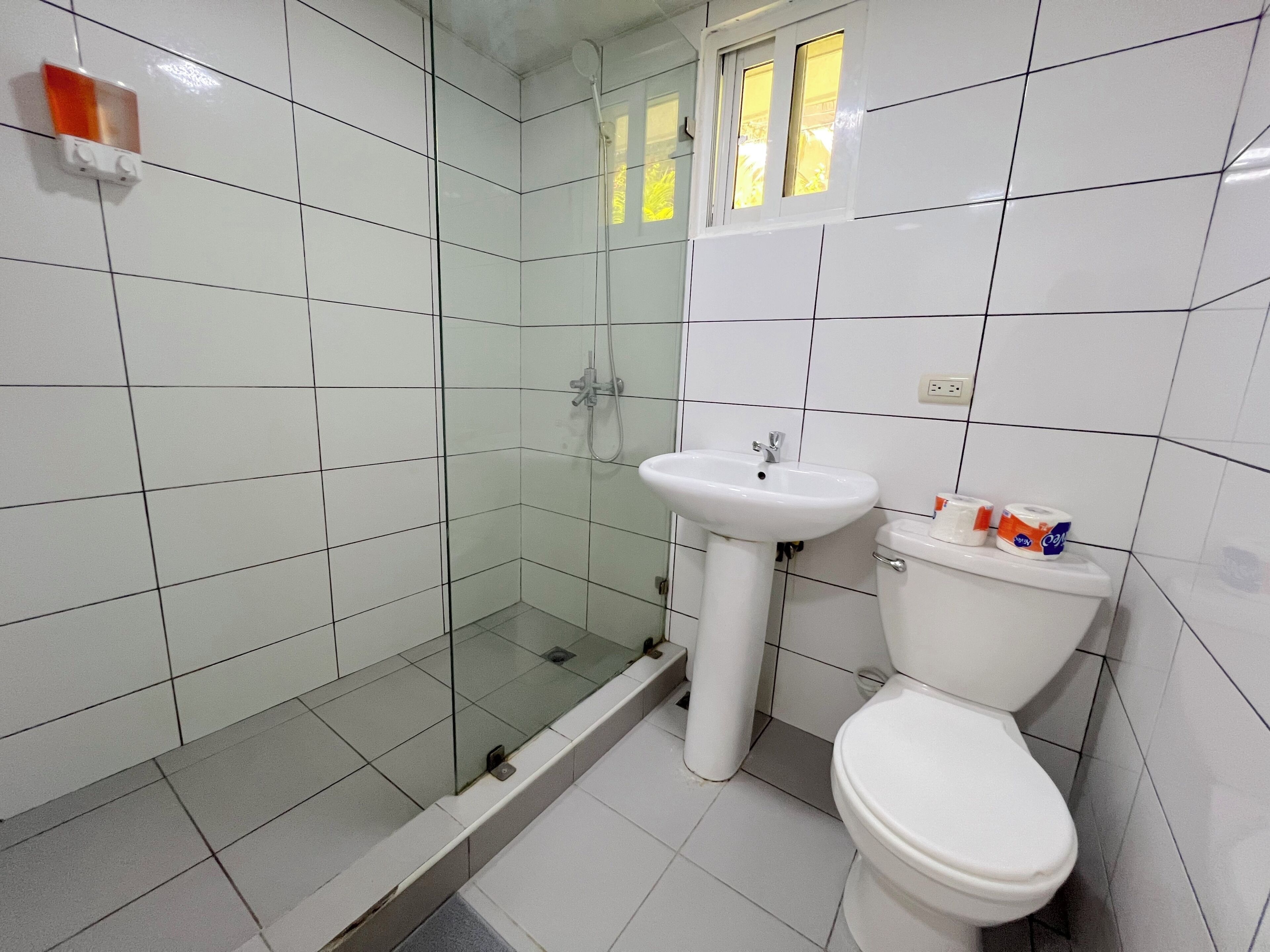 Un bagno con cabina doccia in vetro, lavabo su piedistallo e water.