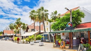 Calle con edificios, palmeras y un restaurante llamado 'Napo'.