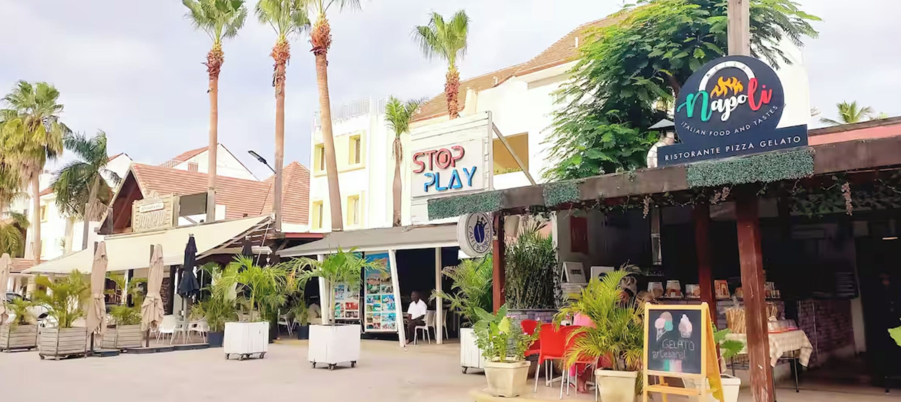 Une rue où se trouvent un restaurant appelé « Napoli » et un magasin appelé « STOP PLAY ».