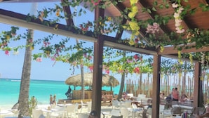 Un espacio al aire libre con mobiliario de mimbre, una terraza de madera y vistas a la playa y el océano.