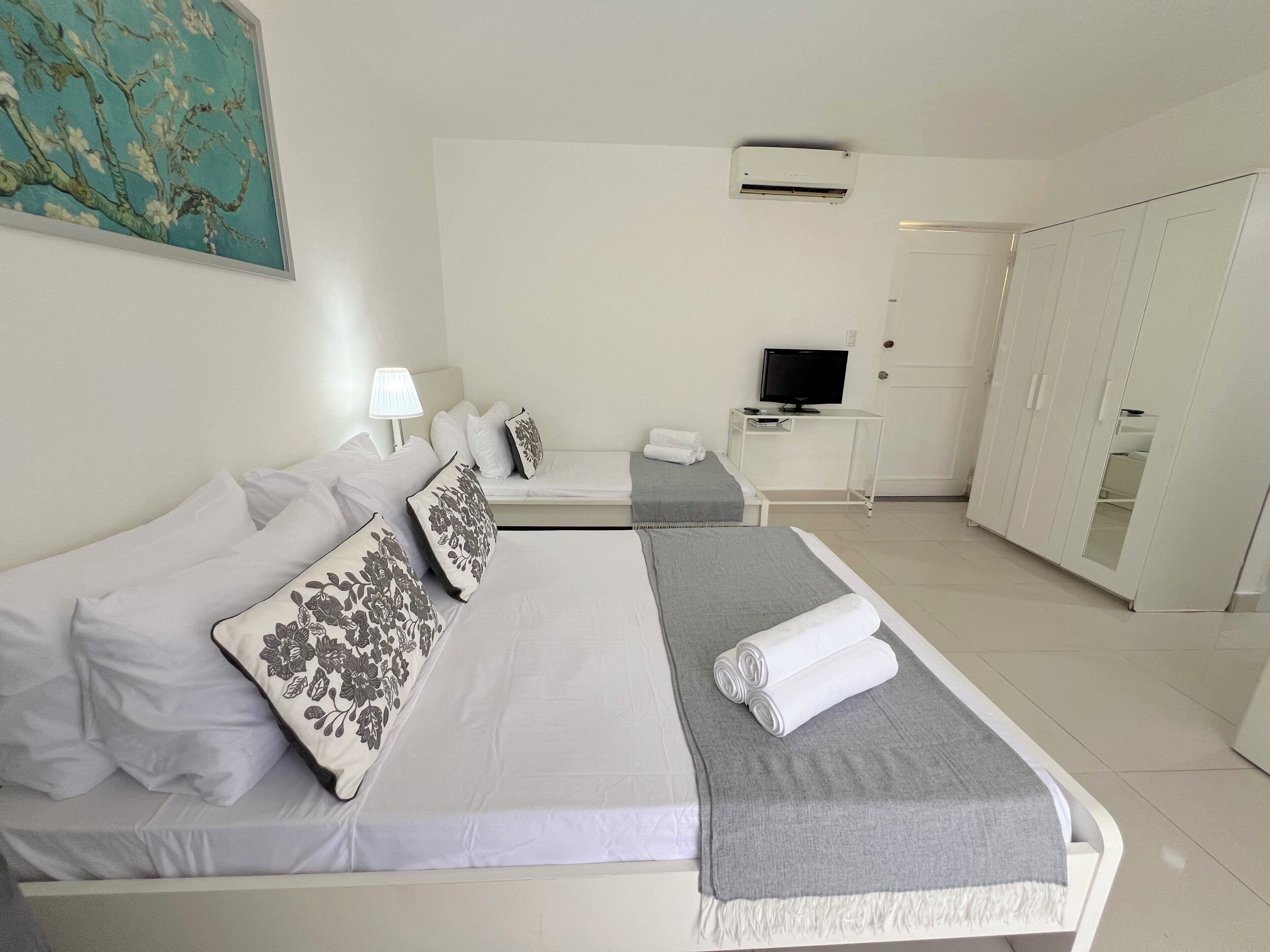 Ein Hotelzimmer mit Bett, Fernseher, Schreibtisch und Kleiderschrank.