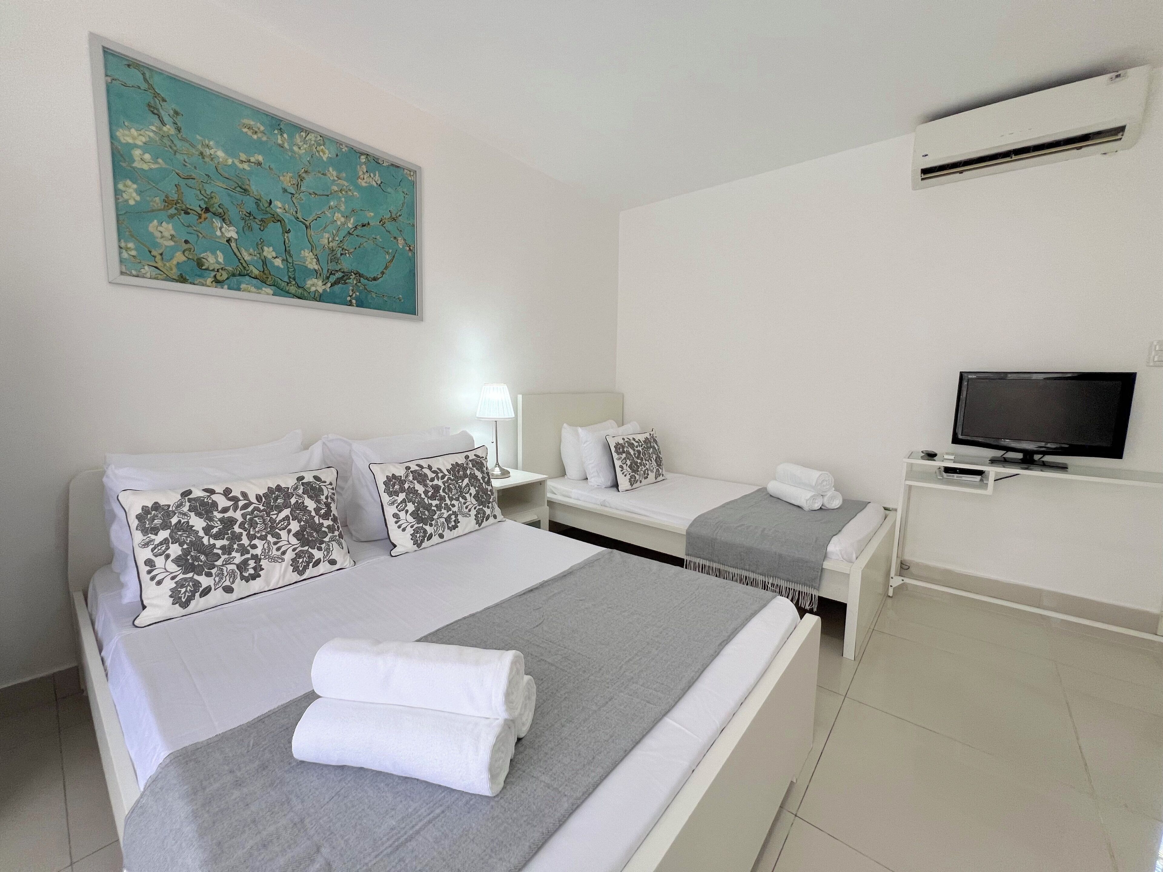Una habitación de hotel con cama, televisión, escritorio y un cuadro en la pared.