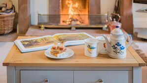 Une table en bois sur laquelle se trouvent un livre, une assiette de nourriture et deux tasses décorées de motifs d’oiseaux.