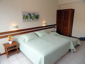 Ein Schlafzimmer mit einem Bett, Nachttischen, einem Wandleuchten, einem Holzschrank und einem gerahmten Bild an der Wand.