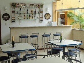 Ein Restaurant mit mehreren Tischen und Stühlen, einem Barbereich mit Flaschenregalen und einer Uhr an der Wand.