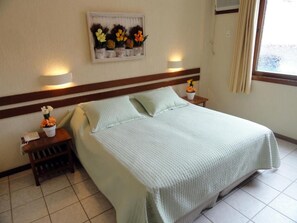 A hotel room with a bed, bedside lamps, a nightstand, and a wall-mounted flower arrangement.