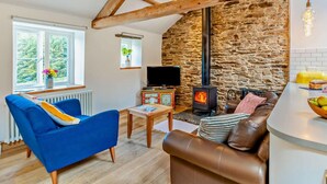 A cozy living room with a stone wall, a fireplace, a television, and a blue sofa. - 1 Bed in Cockermouth (oc-sz160) (Lorton)
