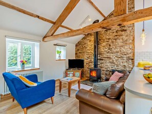 Ein gemütliches Wohnzimmer mit Steinwand, Kamin, Fernseher und einem blauen Sofa.