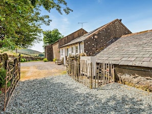 Una propietat rural amb un camí de grava que condueix a un edifici blanc de teulat inclinat.