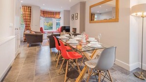 Un comedor con una mesa preparada para cuatro personas, un sofá y un espejo en la pared.