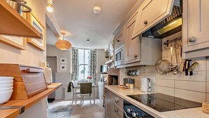 Een moderne keuken met houten planken, een eethoek en uitzicht door een raam.