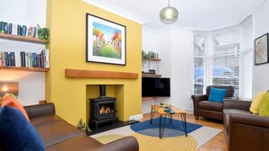 A living room with a fireplace, sofas, a TV, and a bookshelf. - 3 Bed in Keswick (oc-sz118) (Keswick)