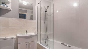 Ein modernes Badezimmer mit einer gläsernen Duschkabine, einem weißen Waschbecken und einer Toilette.