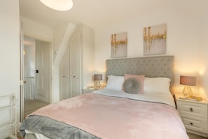 Ein Schlafzimmer mit einem Bett, Nachttischen, Lampen und Kunstwerken an der Wand.