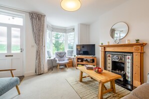 Un salon avec une cheminée, un téléviseur et une fenêtre avec des rideaux.
