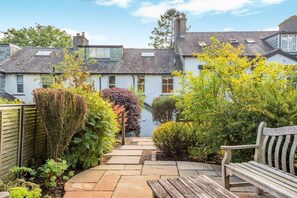 A pathway leading to a house with a garden, a bench, and a small pond. - 3 Bed in Keswick (oc-sz337) (Keswick)