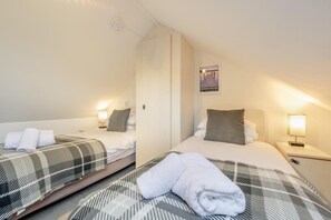 A hotel room with two beds, each with a pillow, a bedside lamp, and a folded towel. - 3 Bed in Keswick (oc-sz337) (Keswick)