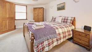 Un dormitorio con una cama, un armario de madera, una mesita de noche y una lámpara.