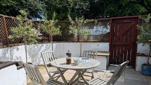 Un patio con una mesa redonda, cuatro sillas, una cafetera y un menú.