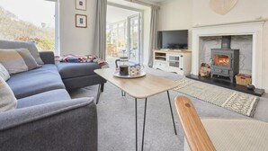 Ein gemütliches Wohnzimmer mit einer Couch, einem Couchtisch, einem Fernseher und einem Kamin.
