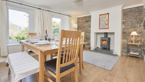 Ein Essbereich mit Holztisch und Stühlen, einem Kamin und einer Steinwand.