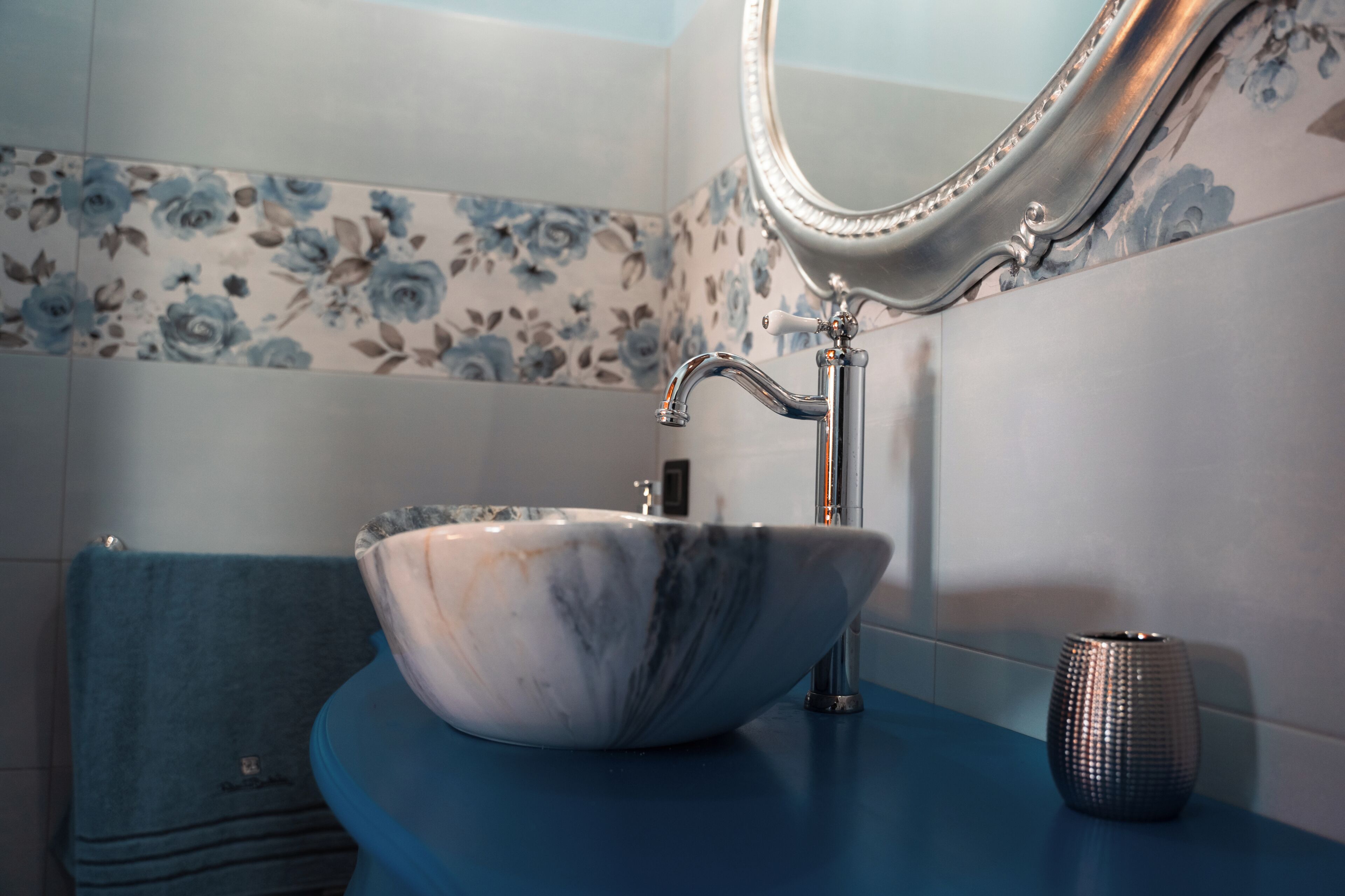 Une salle de bain avec un lavabo en marbre, un miroir et une serviette bleue.