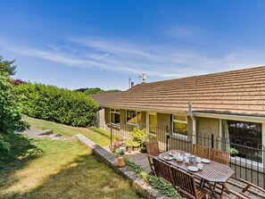 Une maison dotée d’un patio couvert, d’une pelouse et d’un jardin.