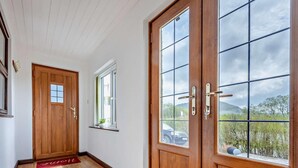 Eine Holztür mit Fenster, ein kleines Fenster und eine rote Matte auf dem Boden.