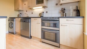 Una cocina con electrodomésticos de acero inoxidable, armarios de madera y salpicadero de azulejos.