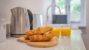 Een keukentrap met croissants, een waterkoker en een glas sinaasappelsap.