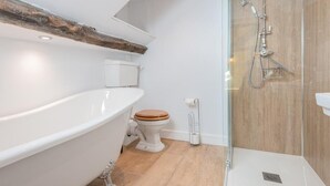 Een badkamer met een vrijstaand bad, toilet en een douchecabine met glazen wanden.
