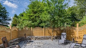 Een terras buiten met stenen trappen, houten stoelen en een houten omheining.