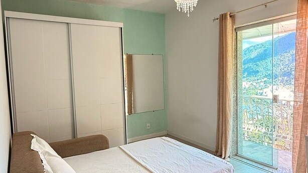 Quarto com cama, guarda-roupa, espelho e janela com cortinas.
