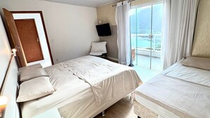 Quarto com duas camas, televisão, porta e vista para o mar.