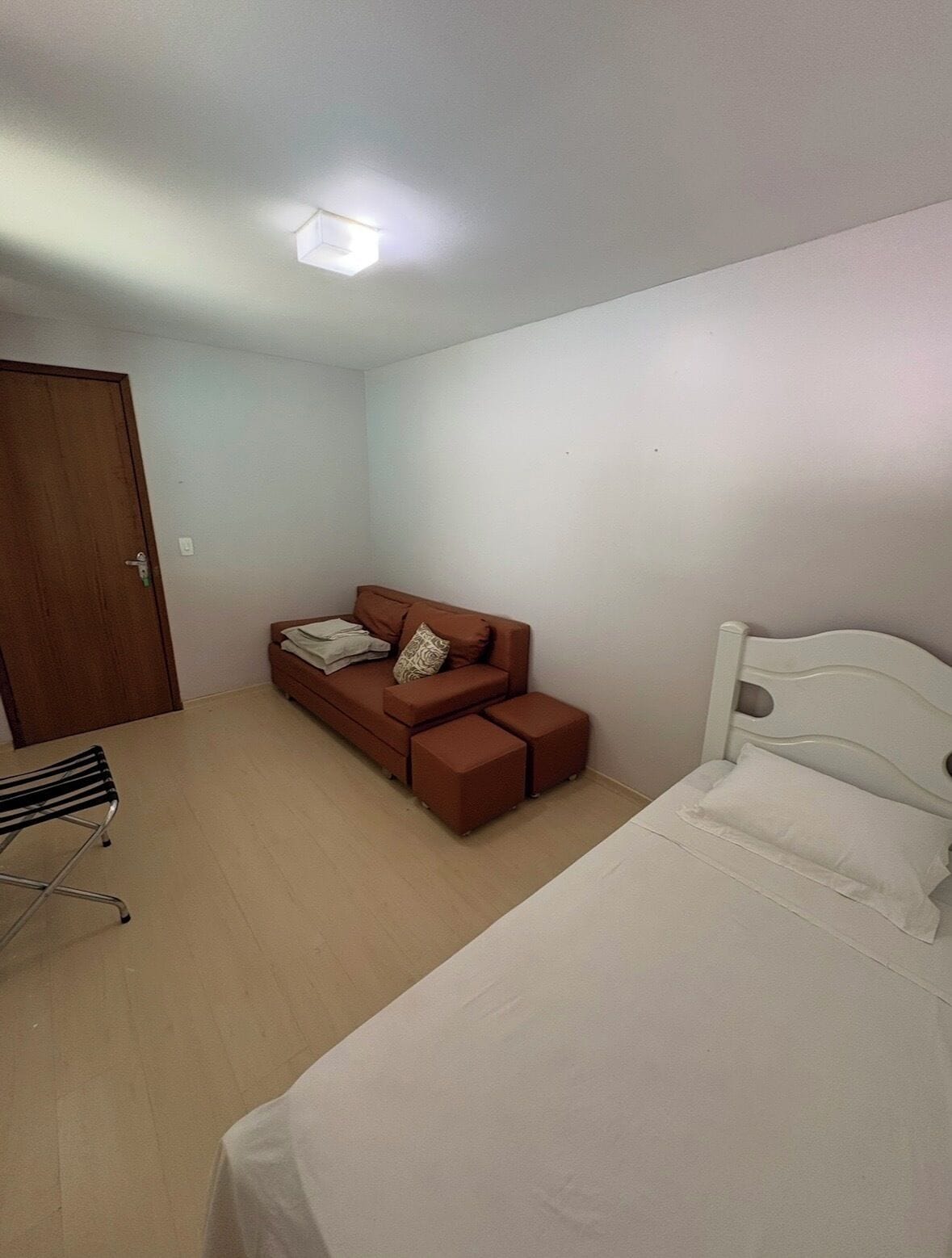 Quarto com cama, sofá, cadeira e porta.