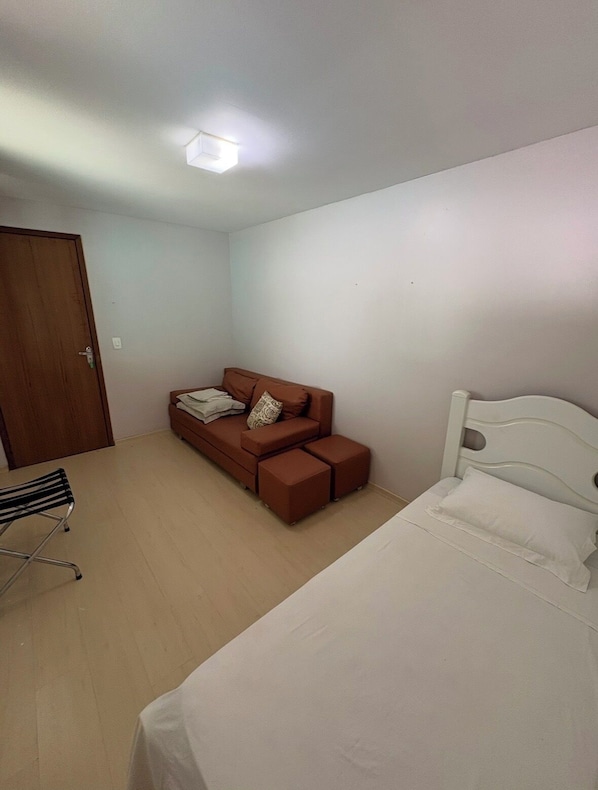 Un dormitorio con cama, sofá, sillón y puerta.