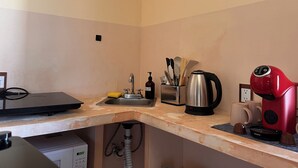 A kitchen with a sink, a coffee maker, a kettle, and a coffee grinder.