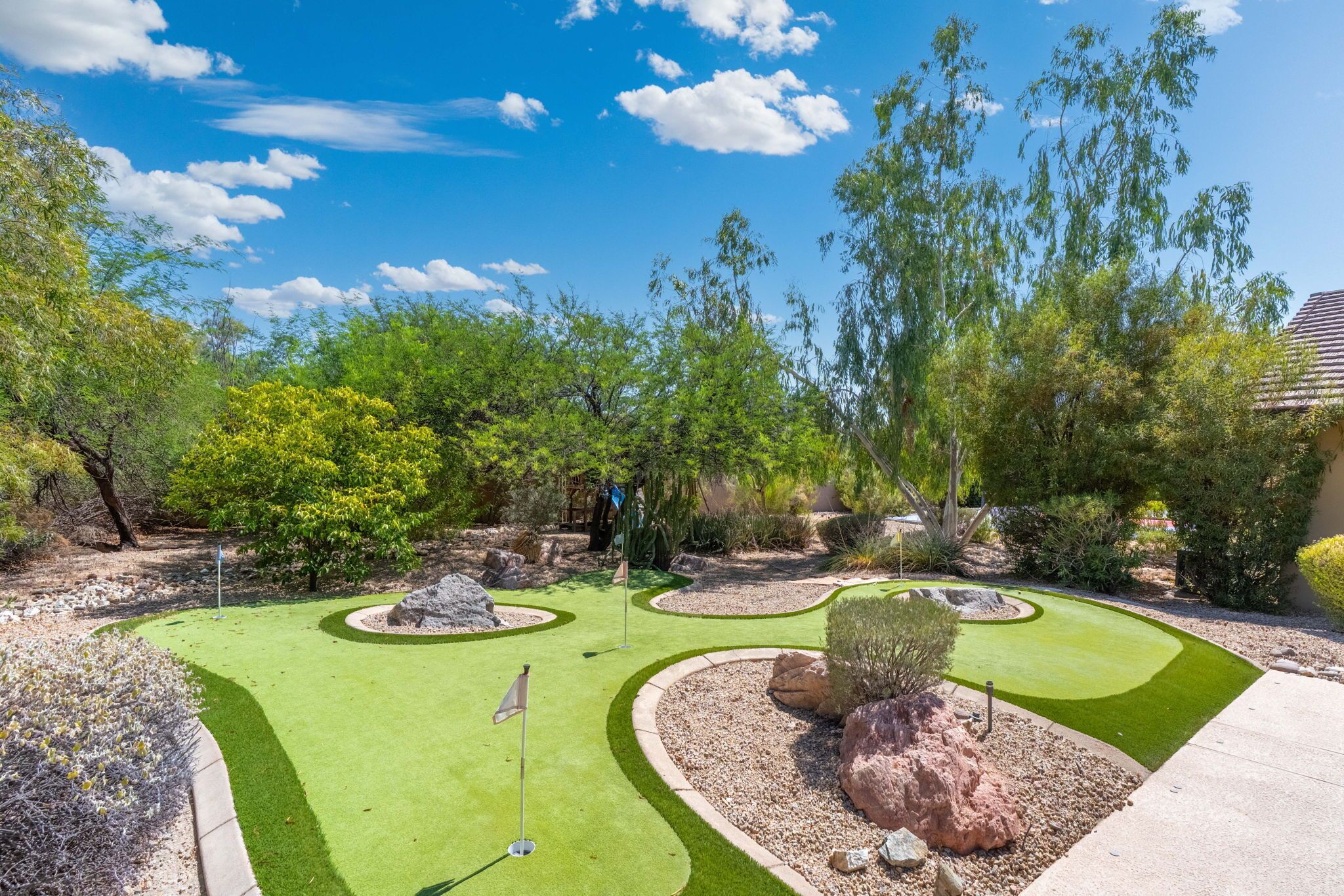 A miniature golf course with multiple holes, surrounded by landscaped areas and trees.