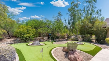 A miniature golf course with multiple holes, surrounded by landscaped areas and trees.