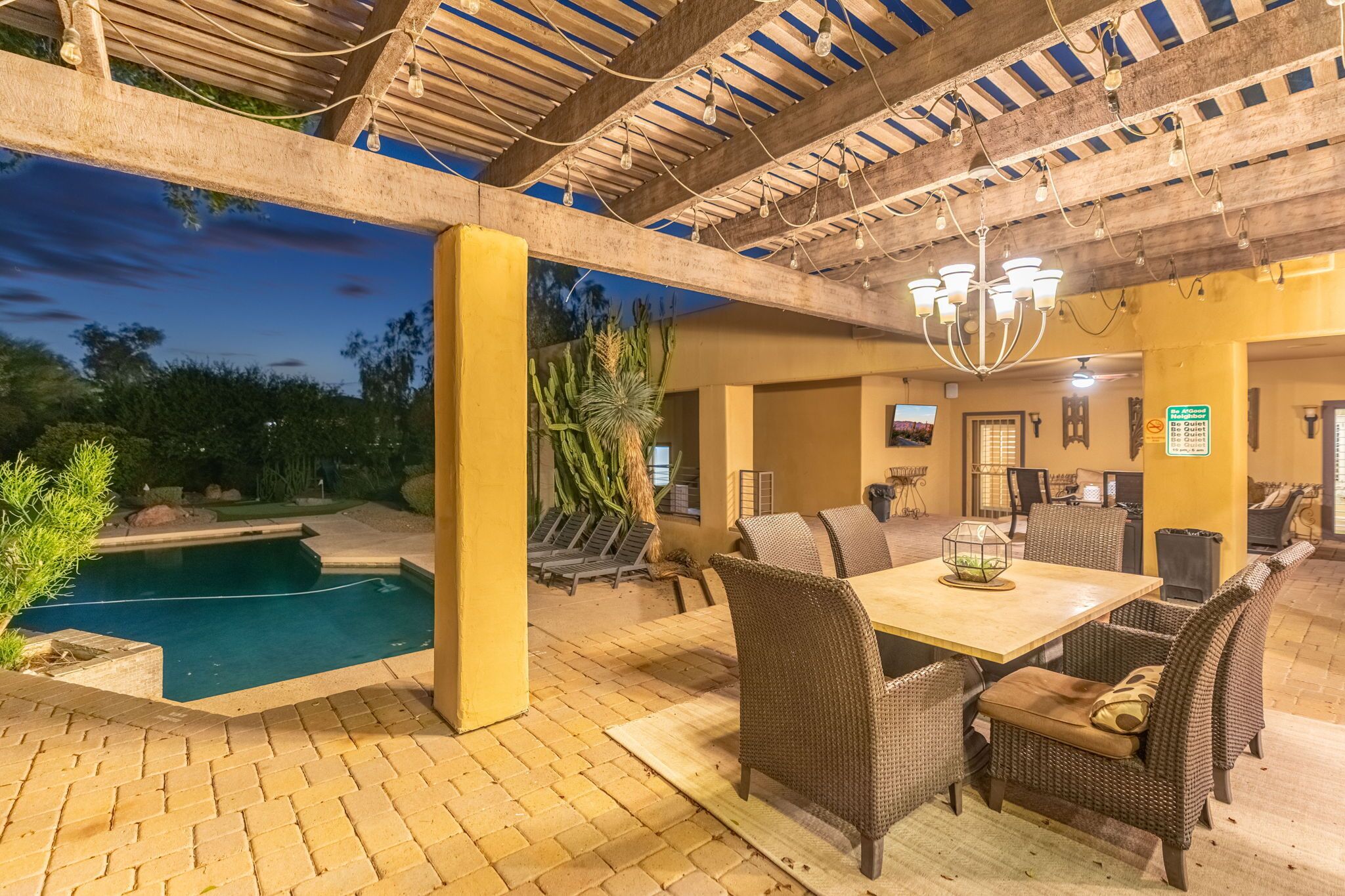 Une terrasse extérieure dotée d’une piscine, d’un espace repas et d’un toit abrité.