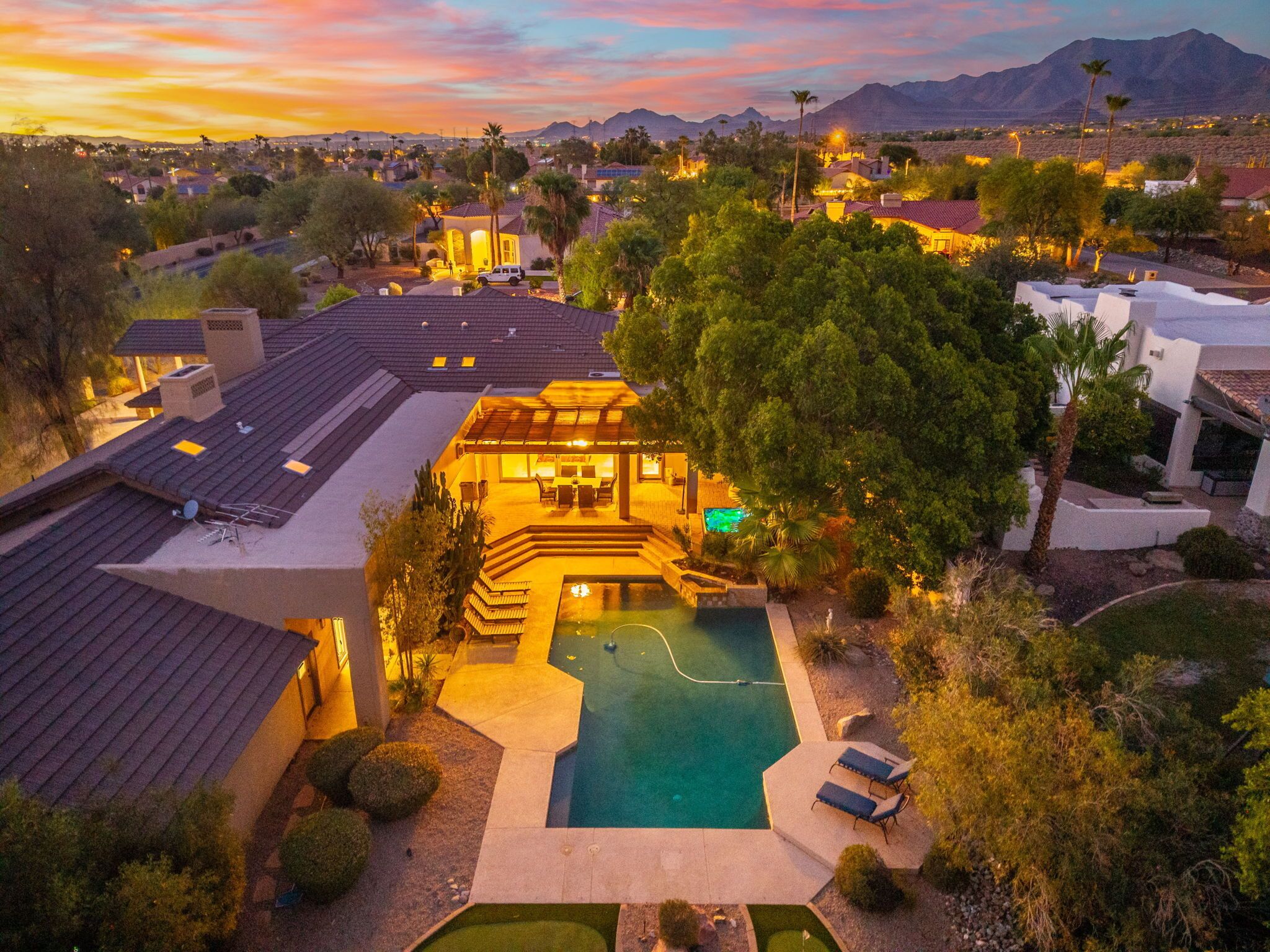 A residential property with a swimming pool, multiple buildings, and a mountainous backdrop.