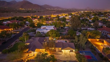 A residential area with houses, a basketball court, and a mountainous backdrop.