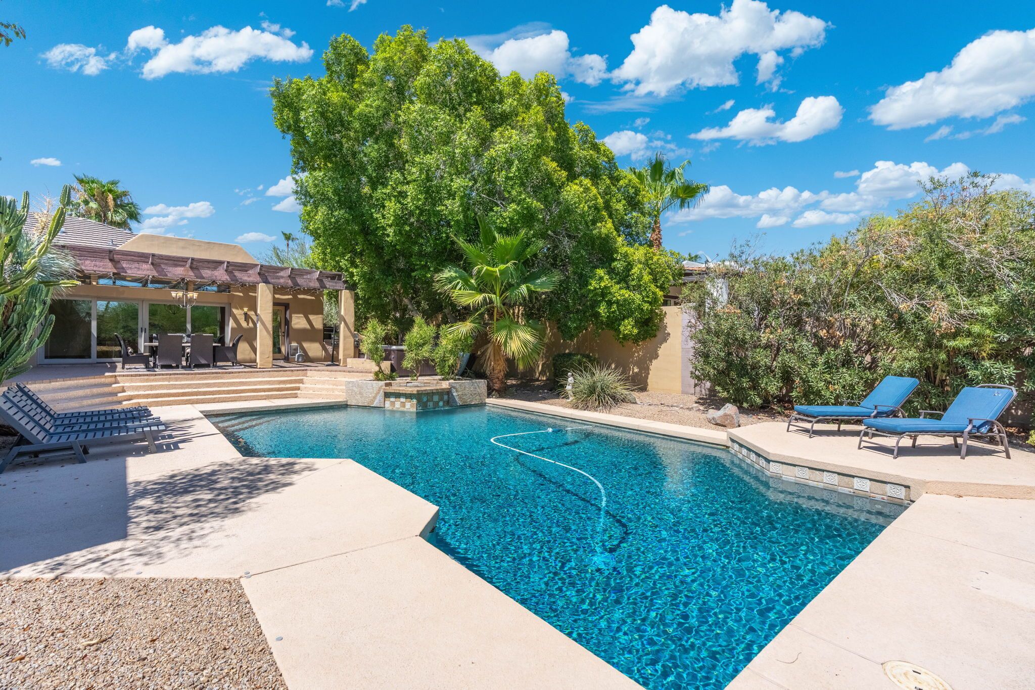 A swimming pool with a pergola and lounge chairs.