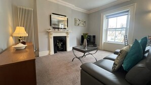 Ein Wohnzimmer mit Kamin, Fernseher, Sofa und Fenster.