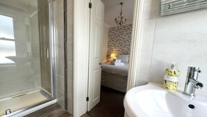 Un baño con cabina de ducha de vidrio, un lavabo blanco y una botella de jabón de manos.