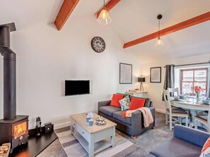 A living room with a fireplace, a sofa, a coffee table, and a dining area with a table set for two. - 2 Bed in Keswick (oc-sz449) (Keswick)